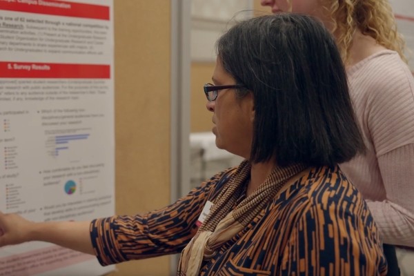 Director Joyce Fernandez listening to a student presentation at the Undergraduate Research Forum