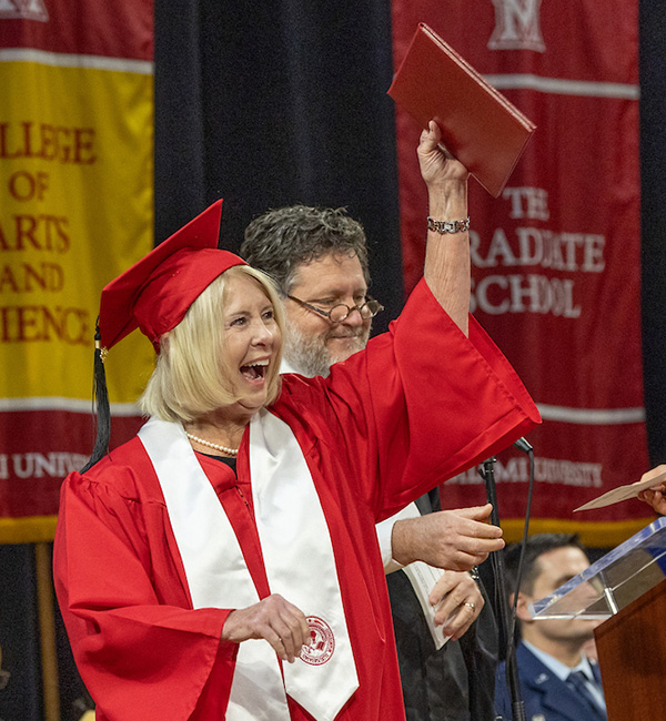 Debbie Brown with her diploma in the air at her graduation ceremony