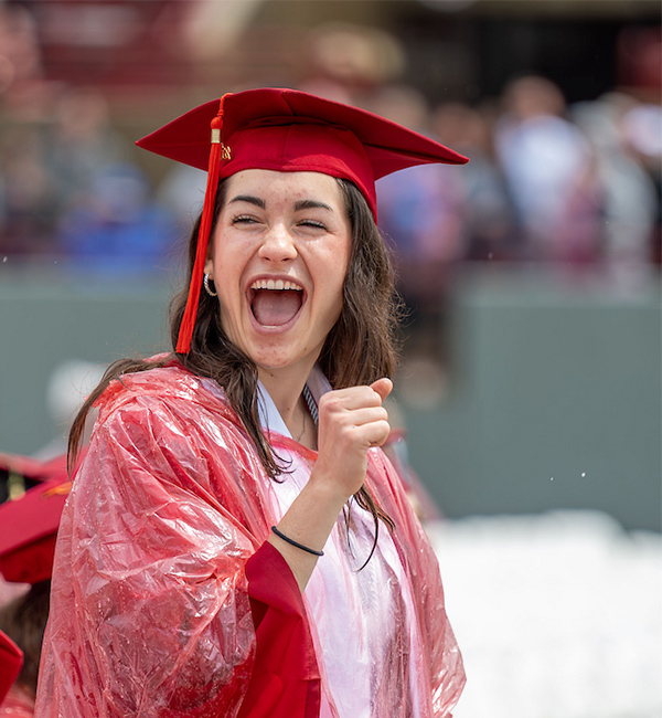 graduating student standing and cheering at commencement