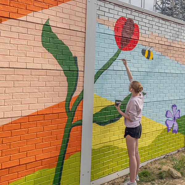 student painting a large tulip on the mural