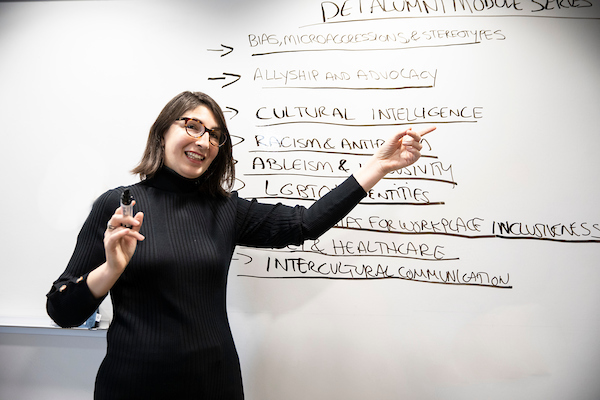 A woman presents class material on the white board.