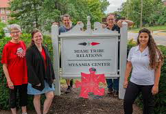Staff members of the Myaamia Center posing around the sign outside their building