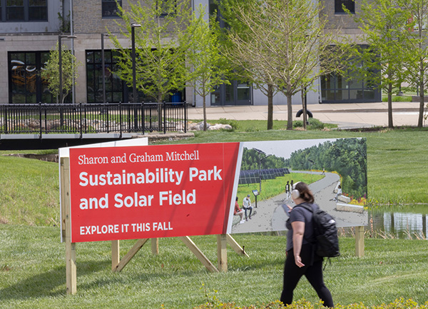 Sustainability Park and Solar Field Explore it this fall banner with a student walking in front of it