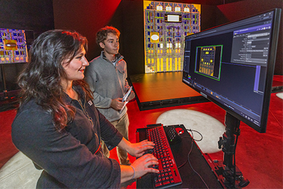 Students engaged in digital media production, working on computers in a classroom setting.