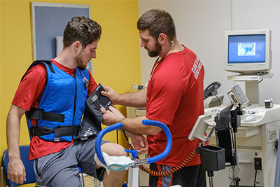 A healthcare professional adjusts a medical device on a patient wearing a rehabilitation vest in a clinical setting.