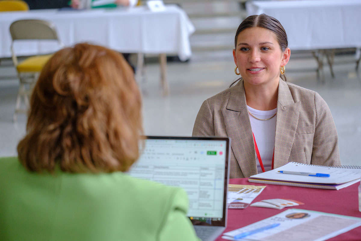 A smiling student sitting in front of a career advisor