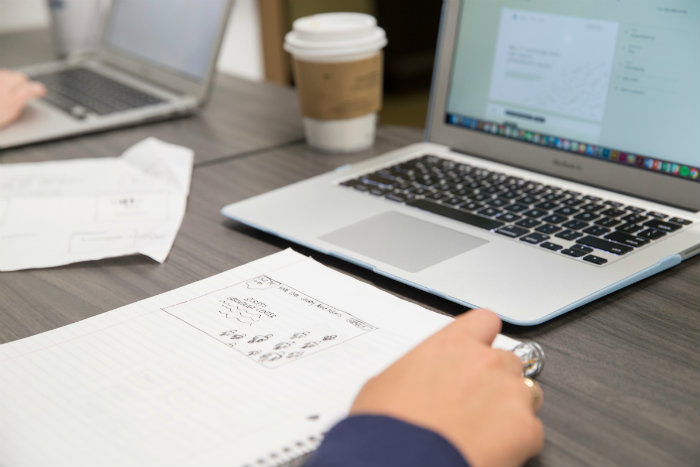 A student working at their laptop with a cup of coffee