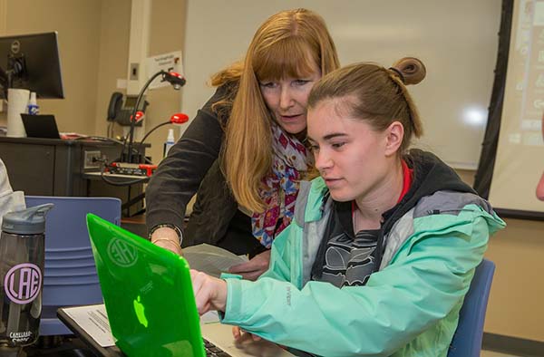 A student and staff member working on a computer