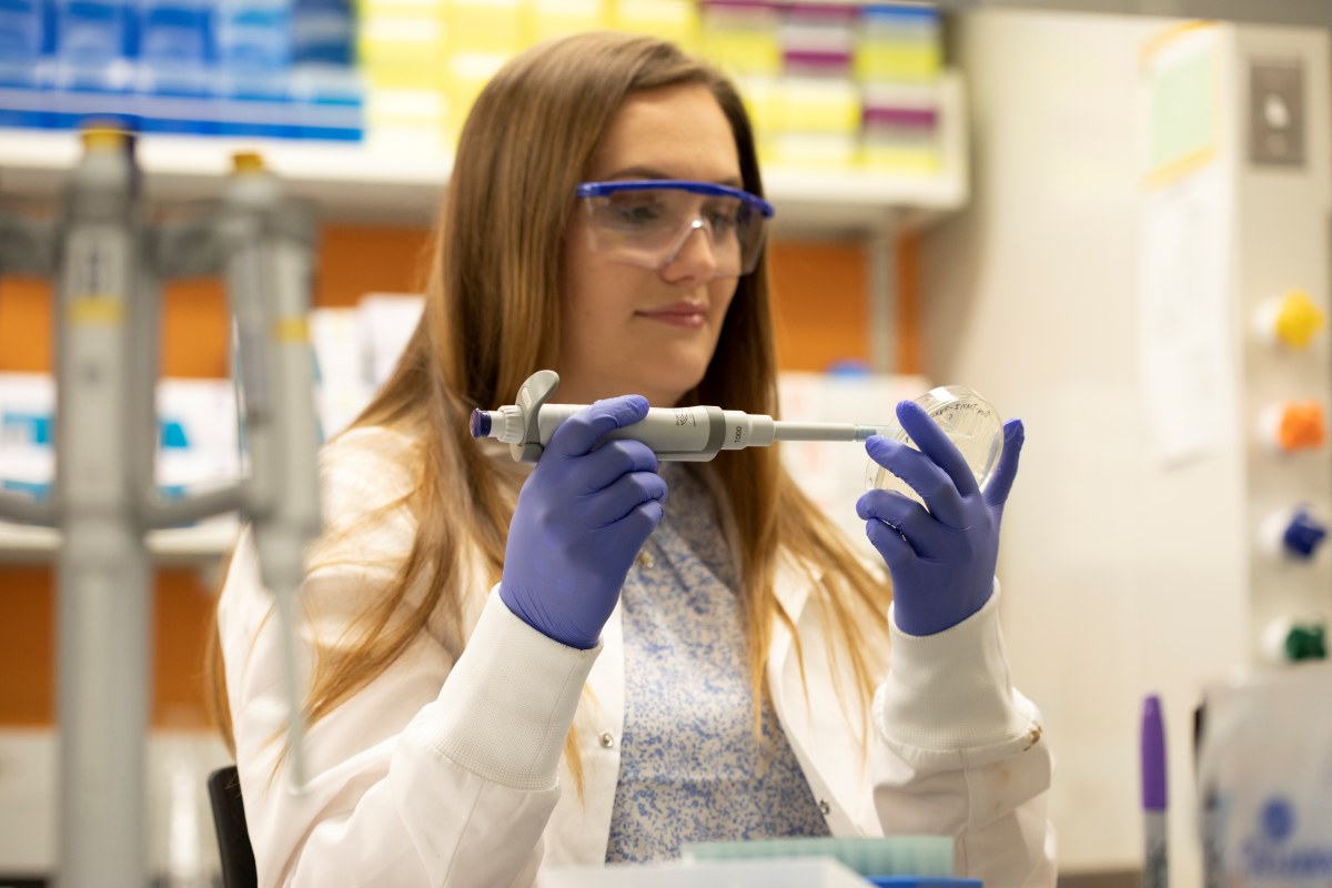 Advanced manufacturing student in a lab holding a petri dish
