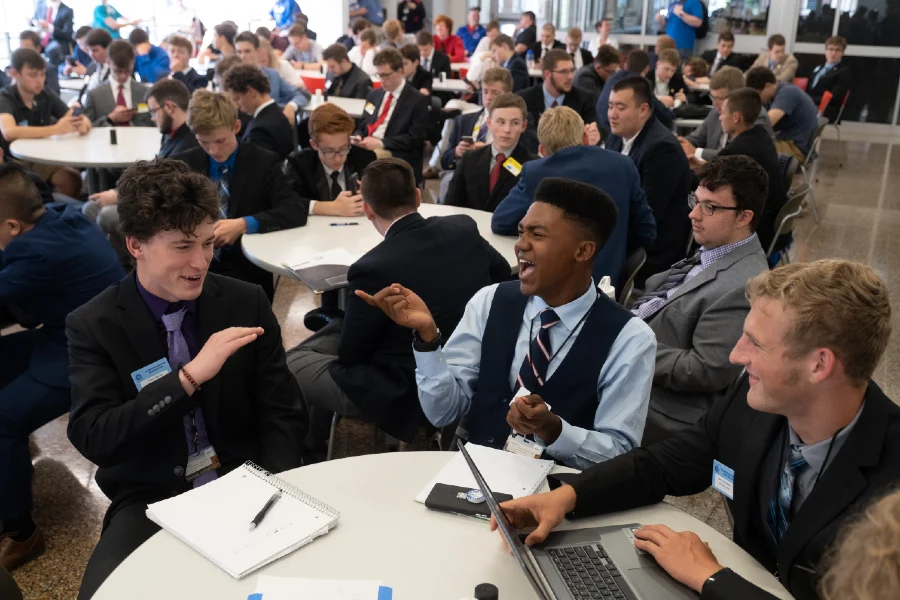 Group of boys sitting at table laughing.