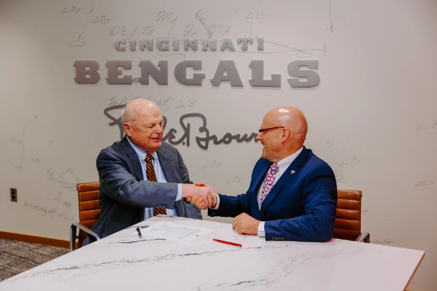 Greg Crawford and Mike Brown shaking hands in front of a Bengals logo