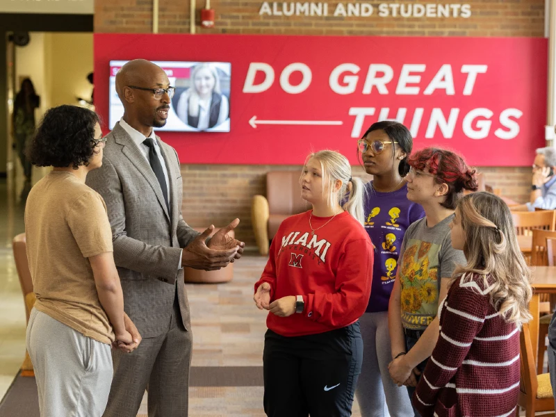 Miami staff member talking with younger students