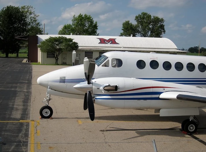 a plane sitting in front of a building that has the miami beveled m on it