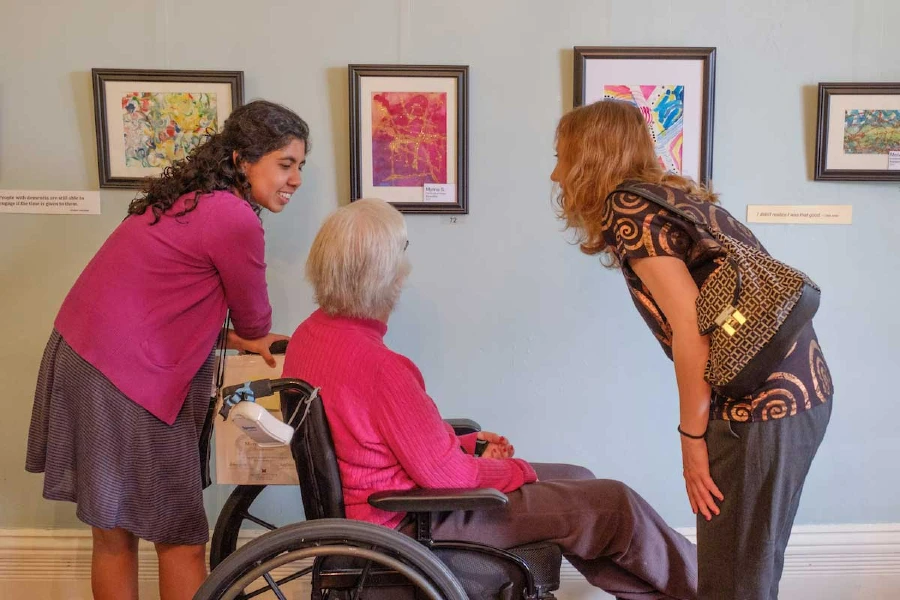 two students talking with en elderly woman in a wheelchair