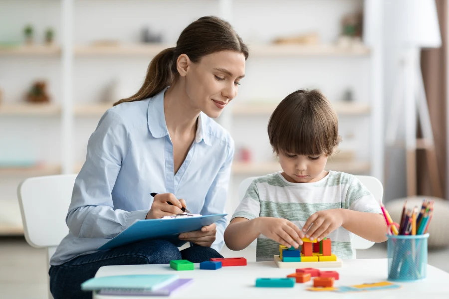 Teacher and student working on a puzzle at a table.