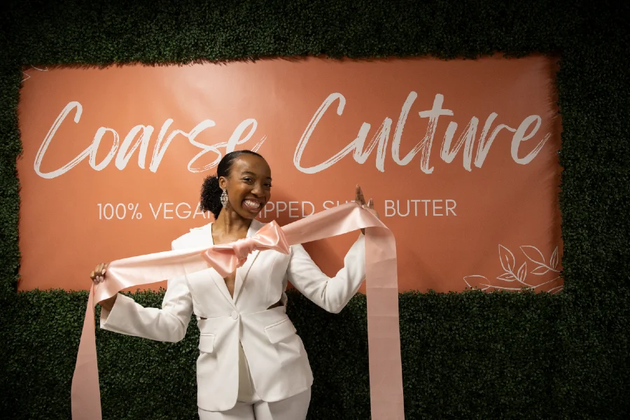 VaLanDria Smith-Lash in front of a sign for her business Coarse Culture