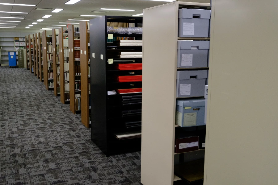 Metal and wood shelves holding books and documents in a library.