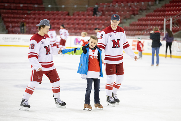 two hockey players skating with a young boy