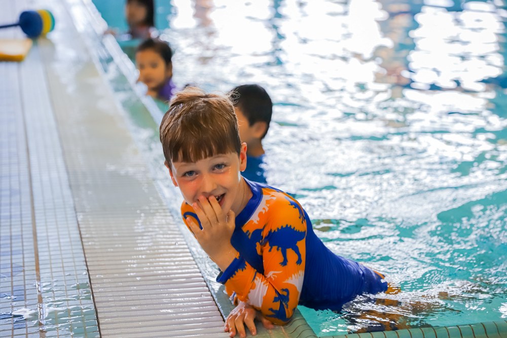 Children taking swimming classes, one child looks at the camera