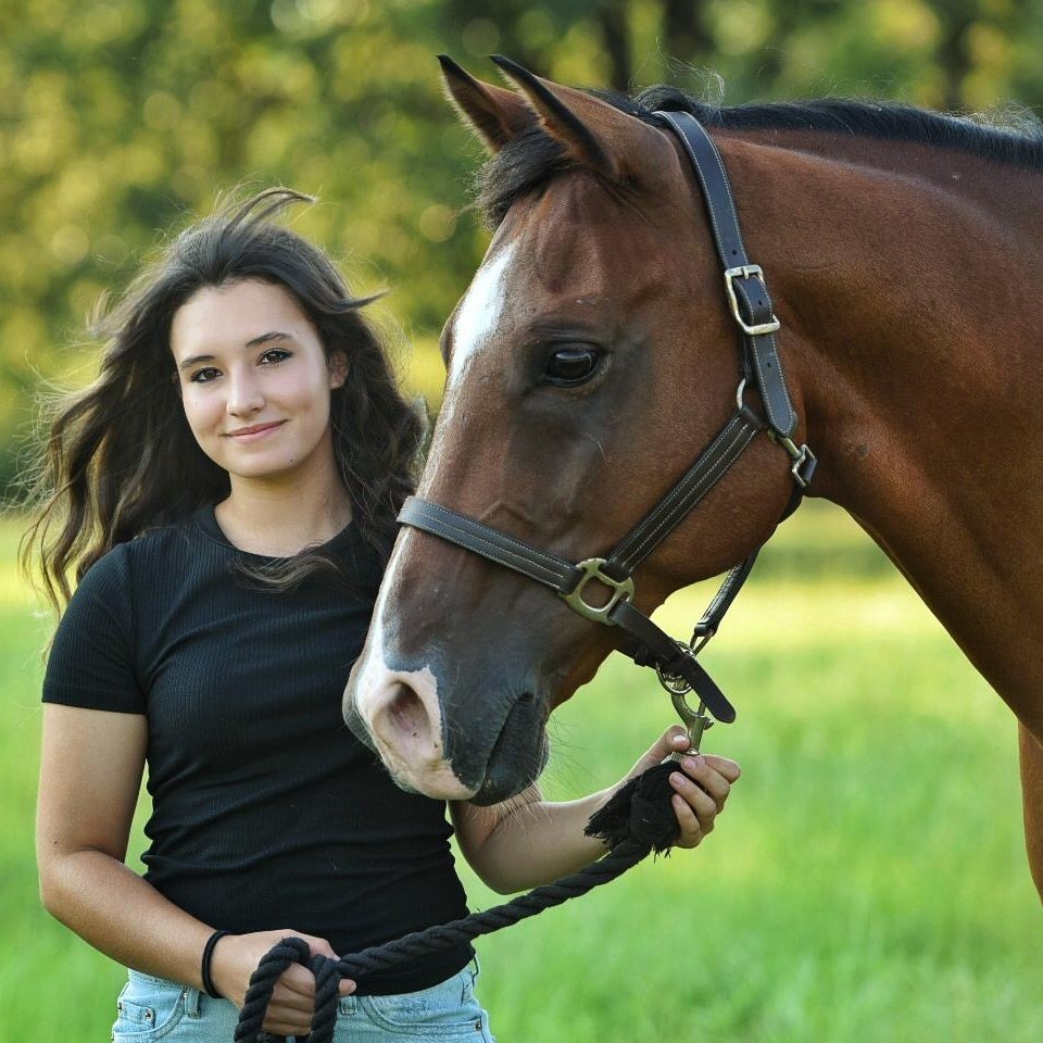 Isabella Davis posing with her horse outside