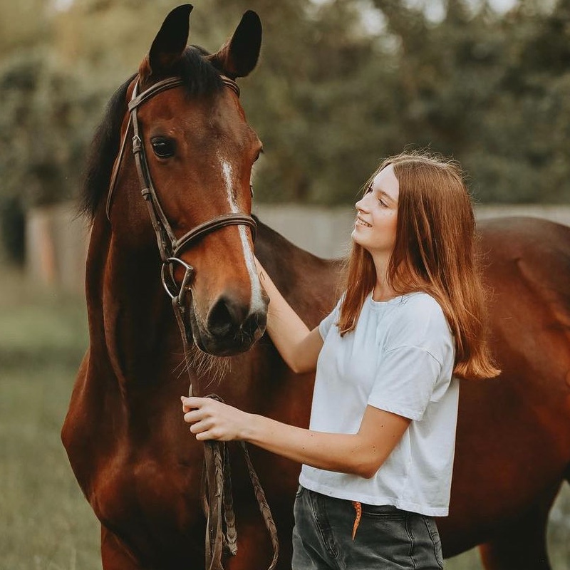 Roberta Cullinan standing next to her horse and petting its head