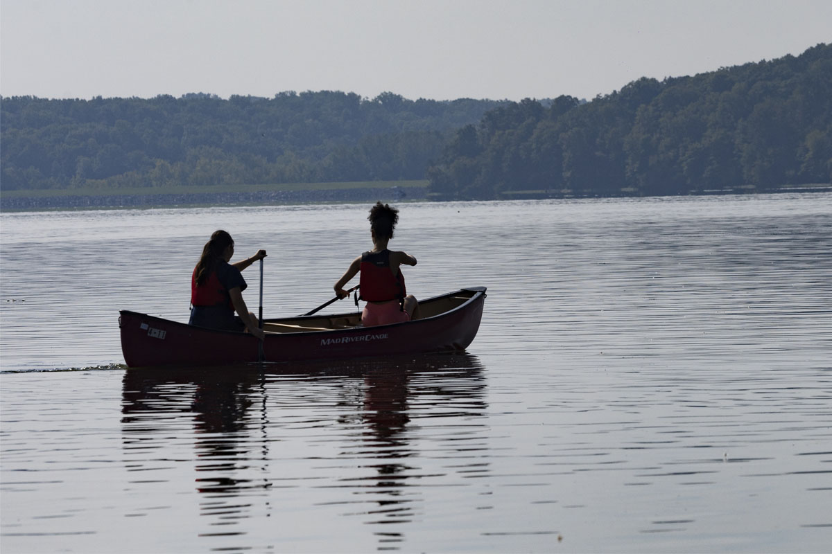 two students paddling on a lake