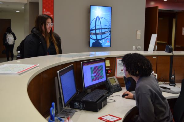 two students talking at a desk 
