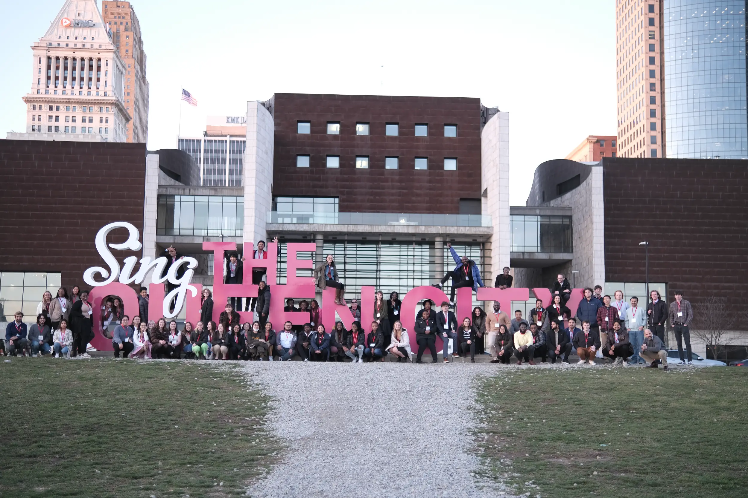 Students sitting on Sing the Queen City sign in Cincinnati, Ohio