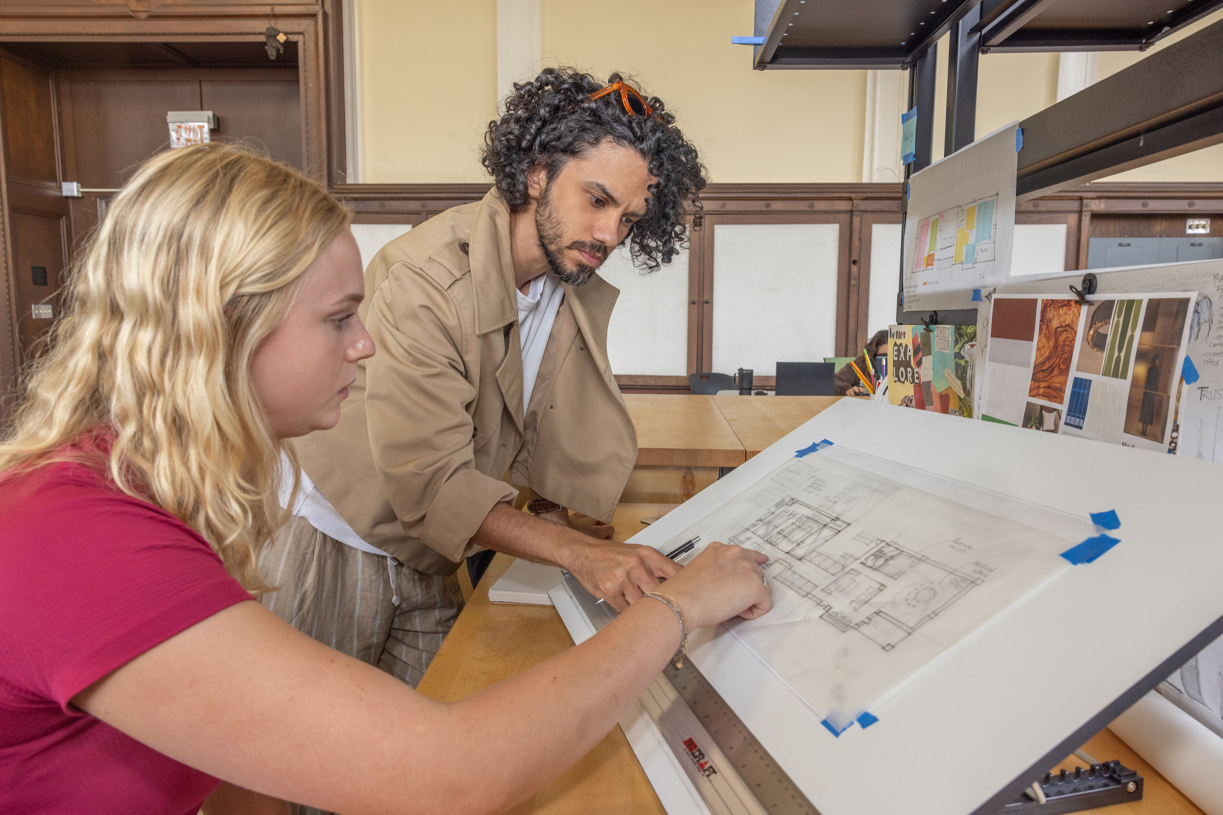 A professor looks at a blueprint with a student.