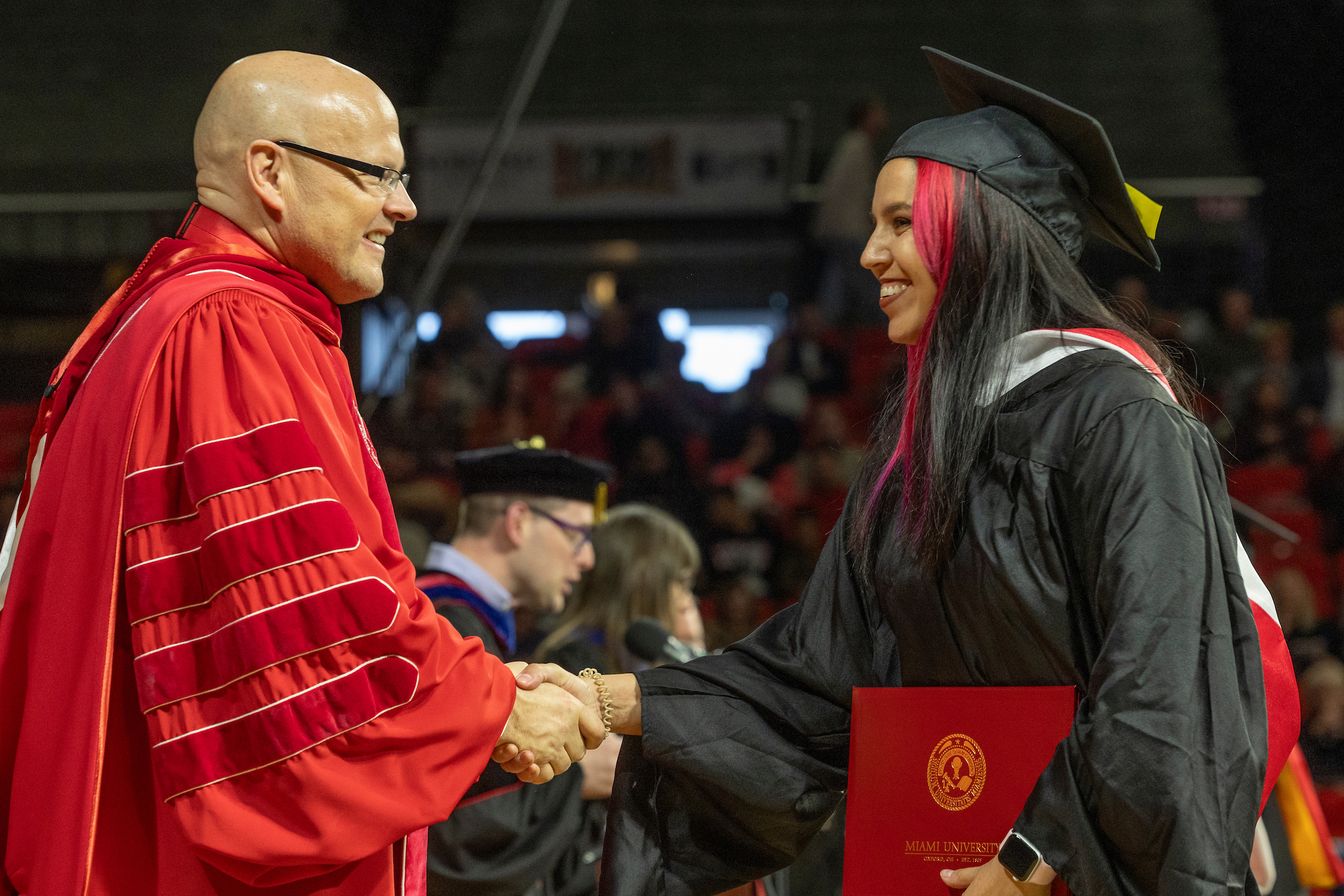 An advanced degree graduate shakes hands with President Crawford at a commencement ceremony.