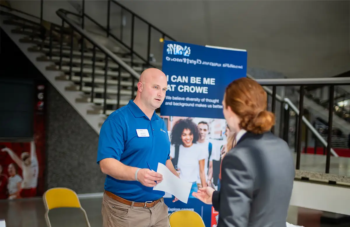 Student dropping off a resume with an employer at career fair