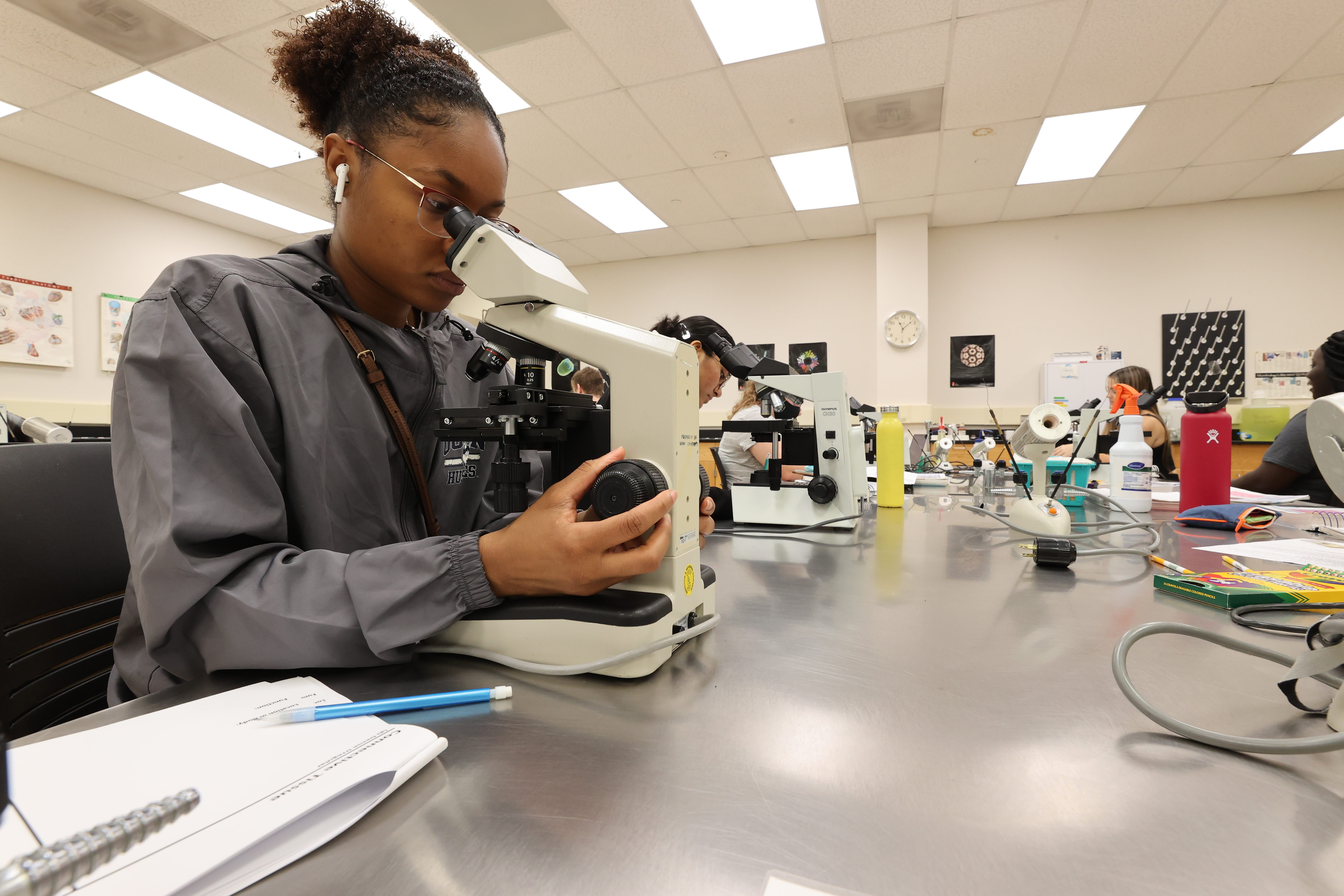 A student looks through a microscope while in a class.