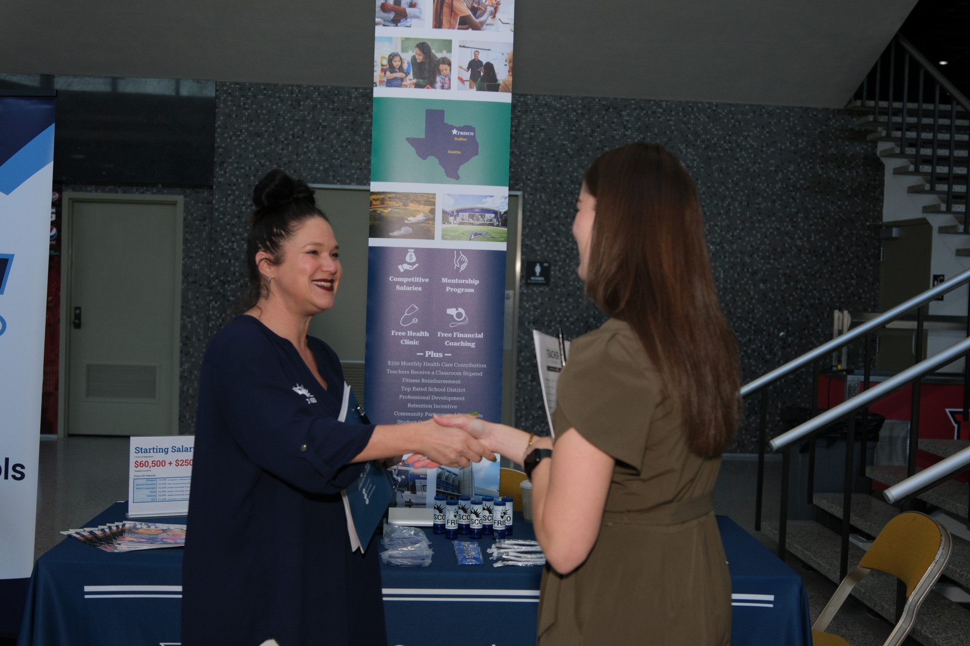 A student shakes hands with an employer at a career fair.