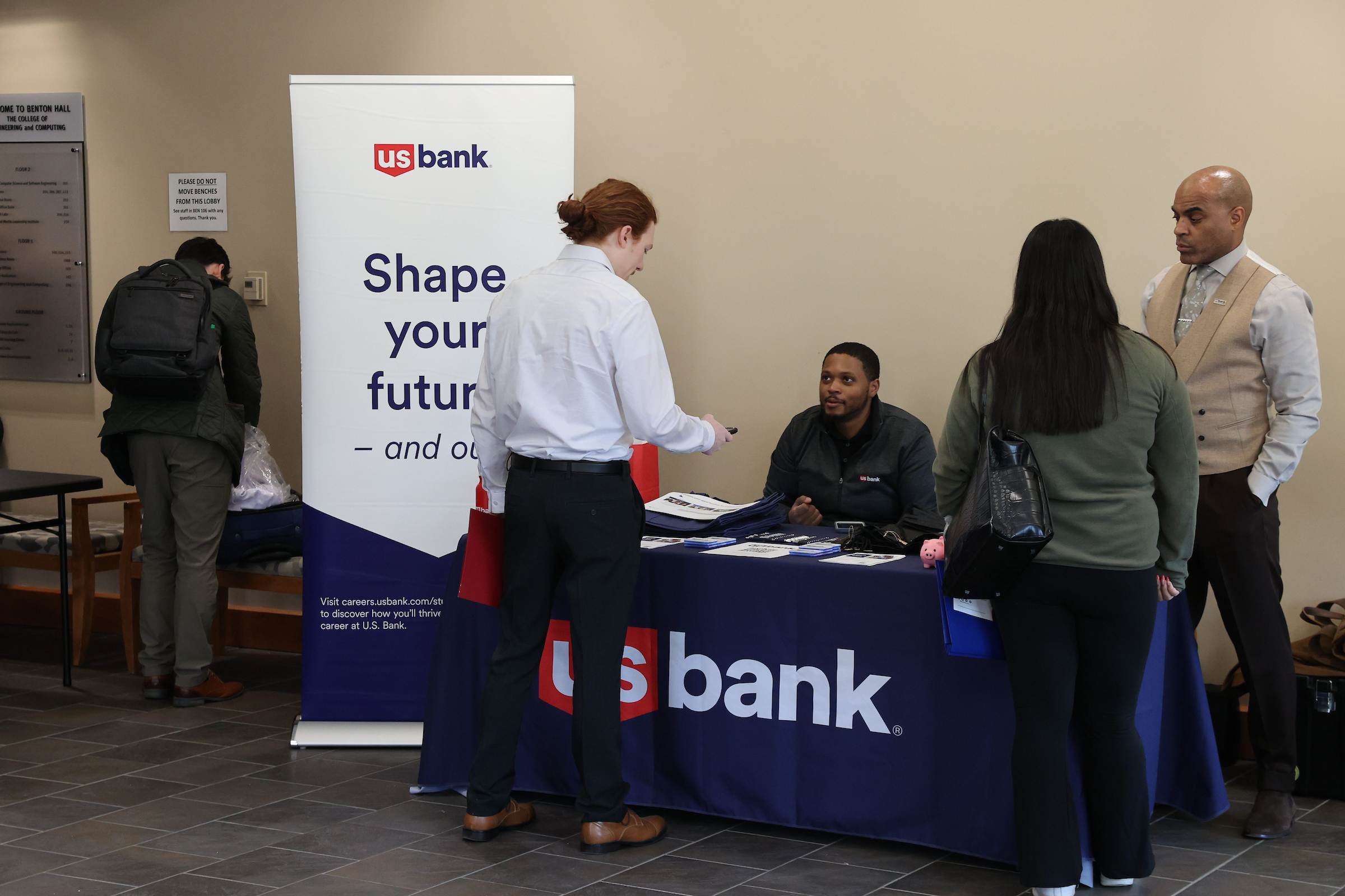 Two employers speak with two students at a networking event.