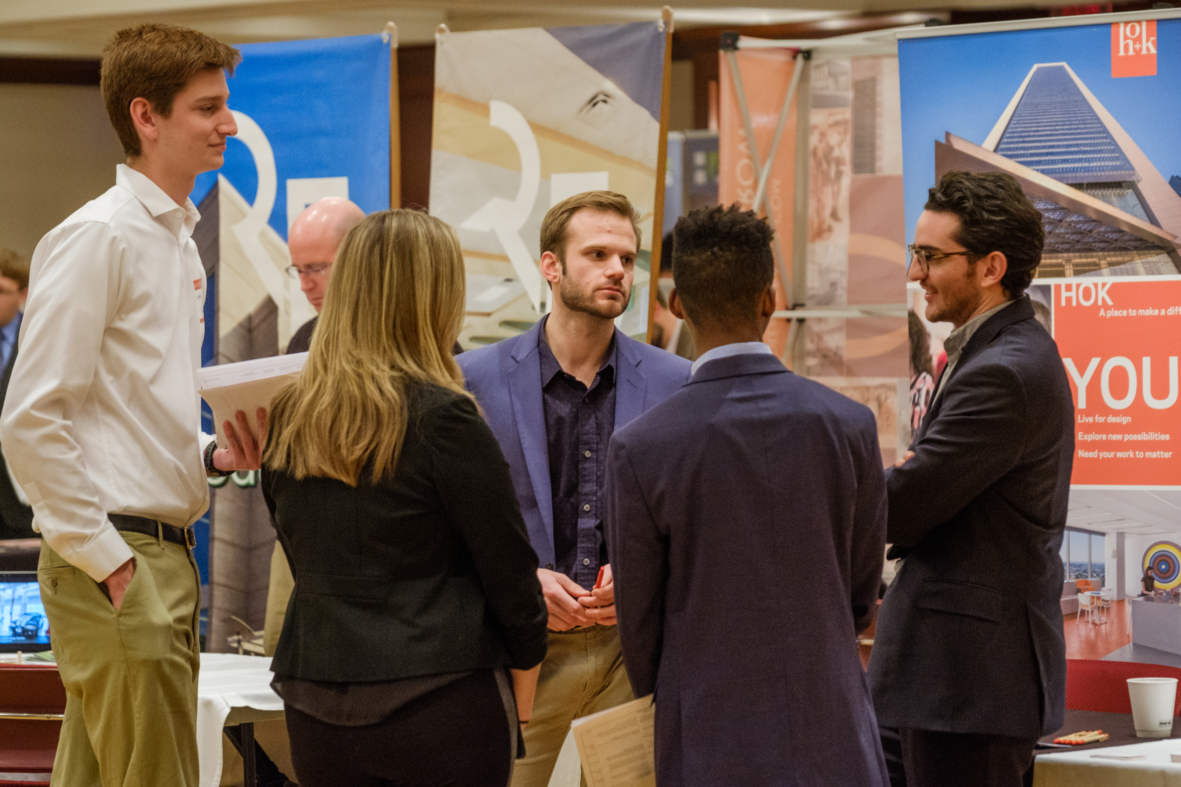 An employer speaks with a group of students at a career fair.