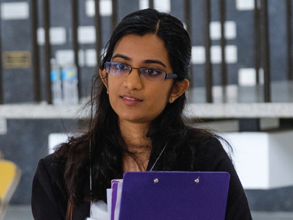 femaie student standing in a classroom holding blue folders