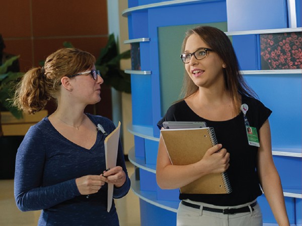 Two female students talking while walking together in a hallway