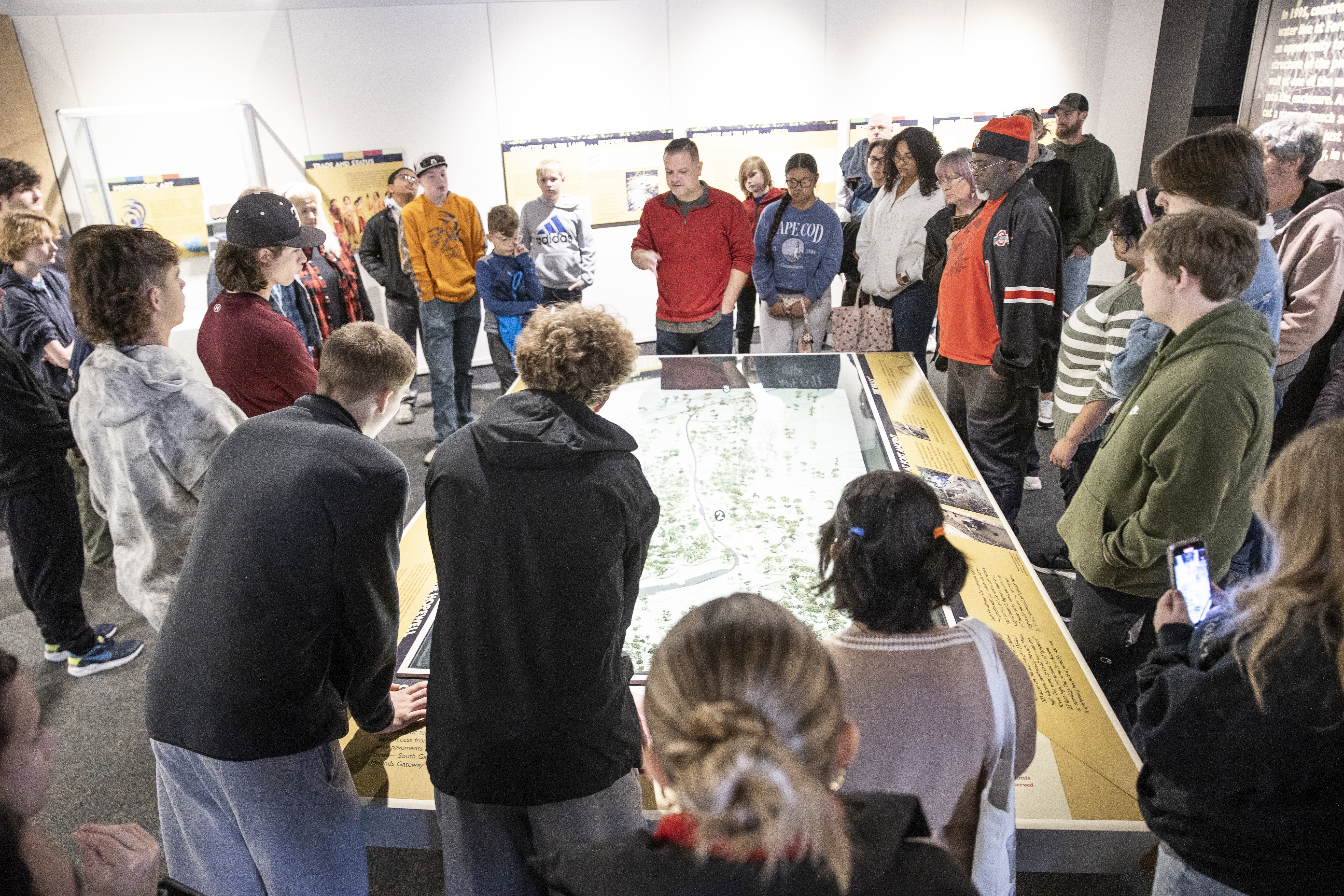 A group of students look at a map display with a professor.