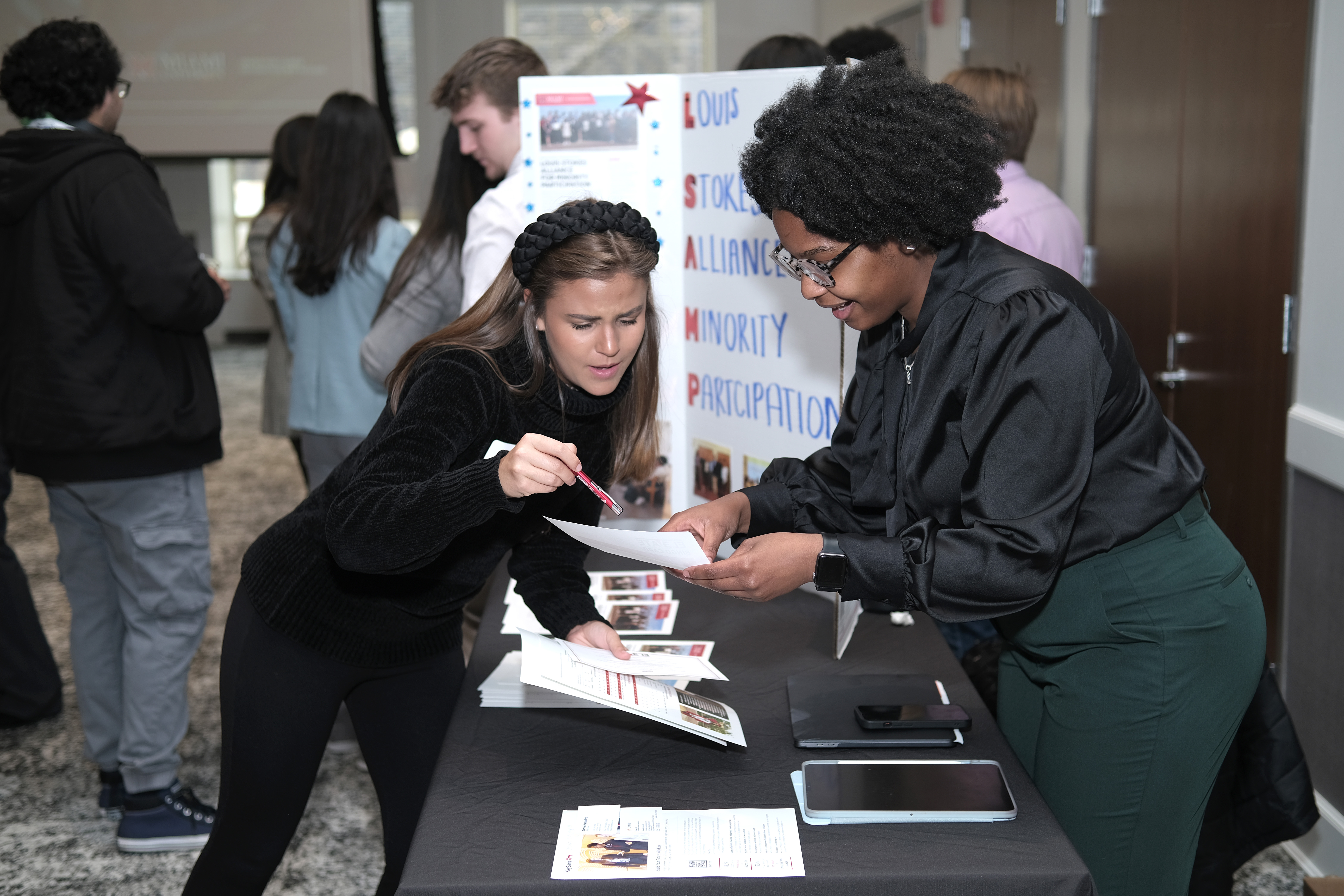 A student shows an employer a flyer at a reverse career fair.