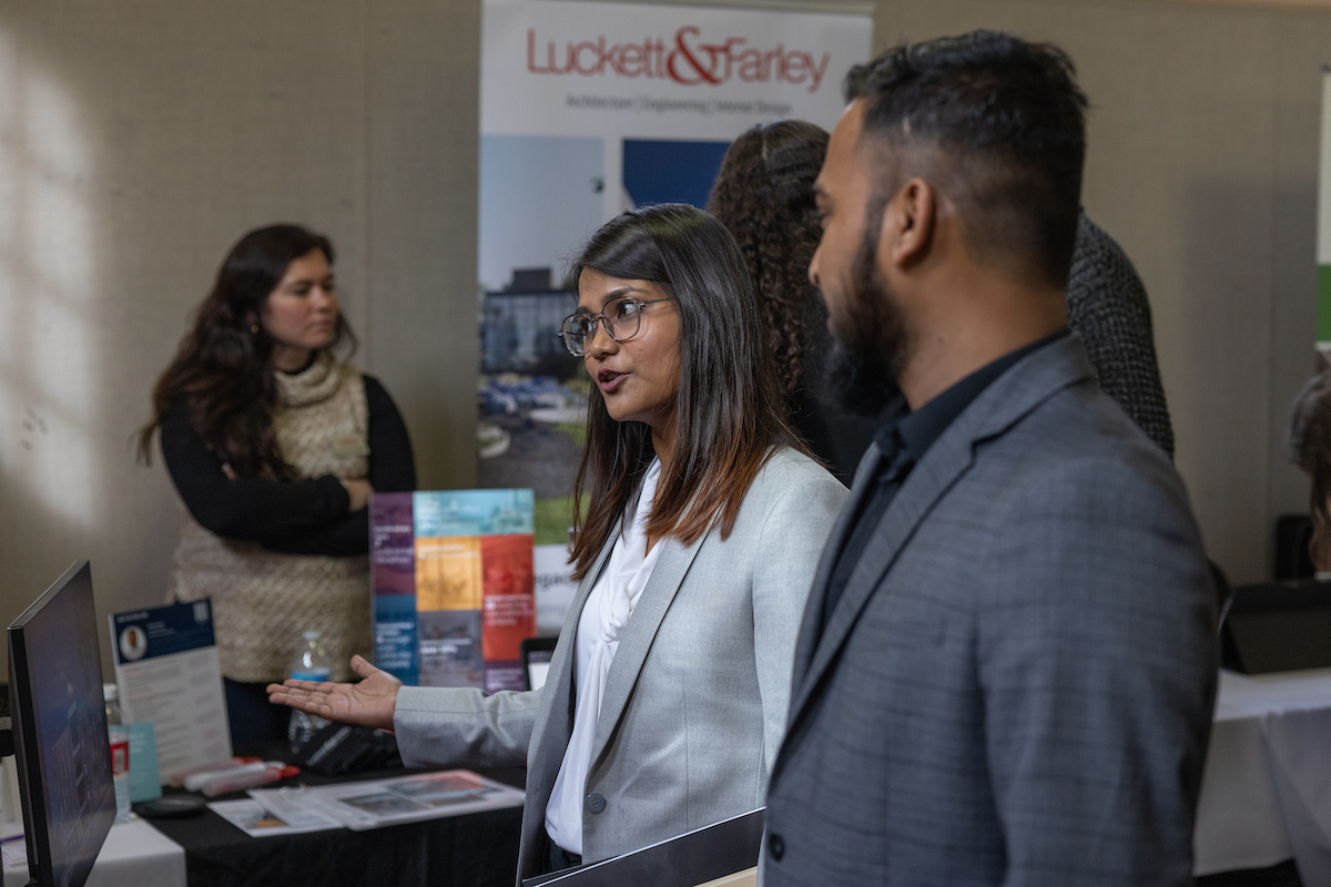 Two students speak with an employer at a career fair.