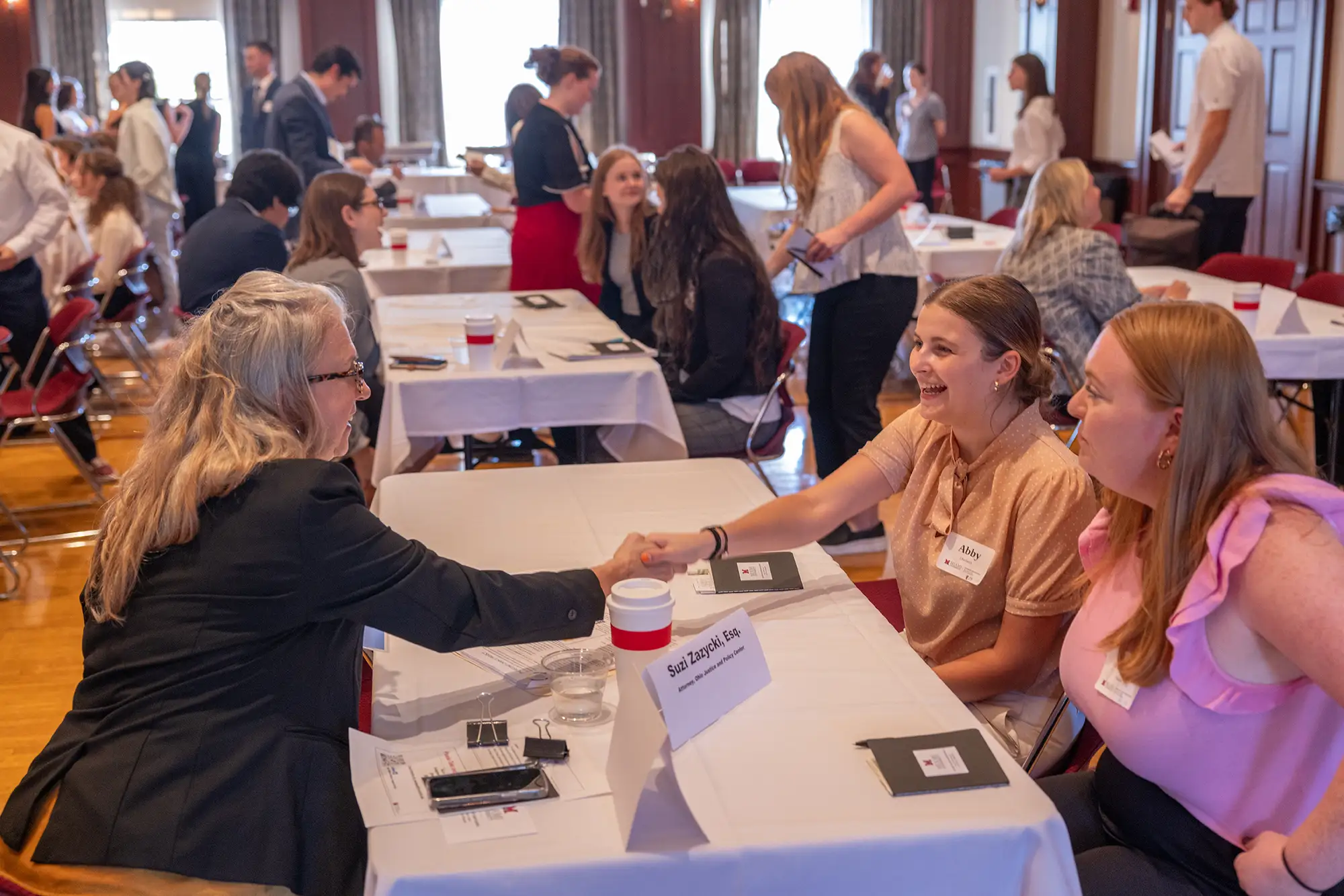 A Miami Alumni shakes hands with a student