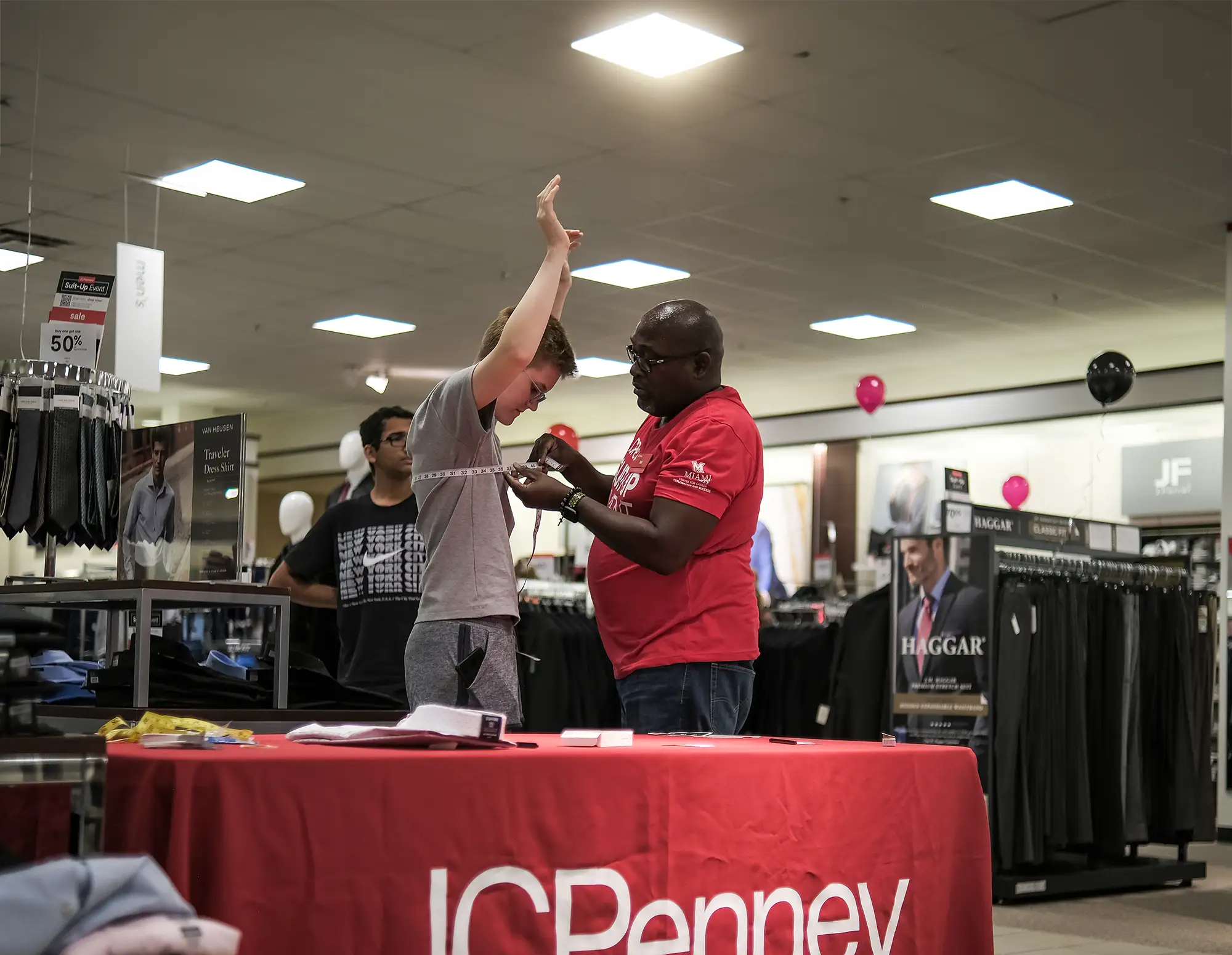 JCPenney employee measures a Miami student to help him choose a suit