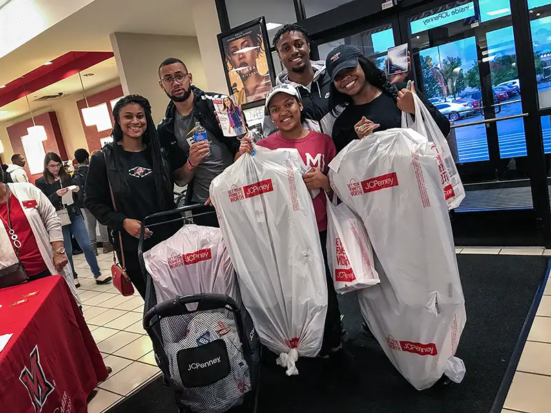 Miami students holding up new suits purchased at JCPenney Suit-Up before leaving