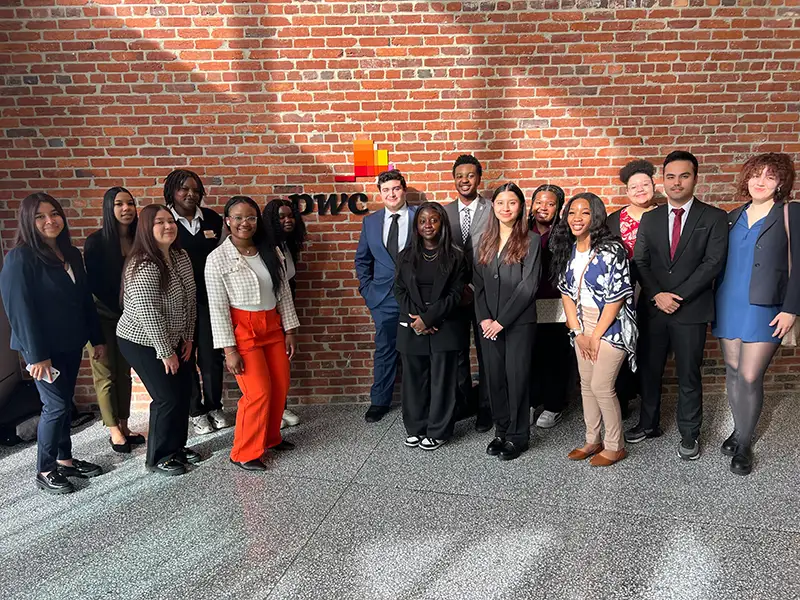 Career Academy participants pose in front of a pwc logo.