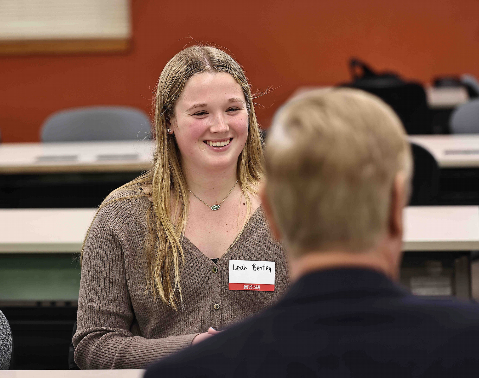 A student smiles while speaking with an employer at a networking event.