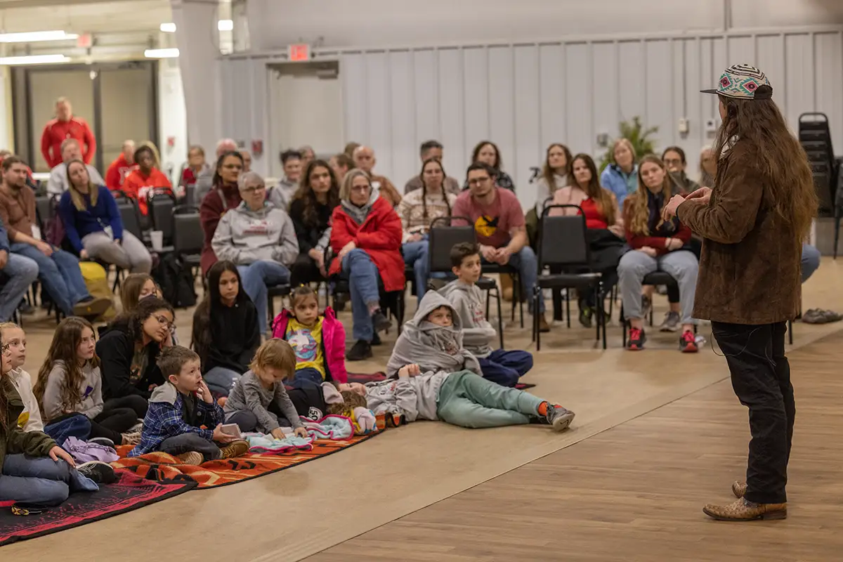 A student addresses a seated crowd of younger students.