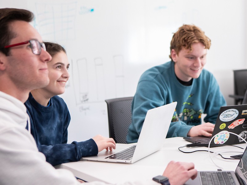 Team of students working on computers around table