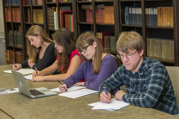 student completing evaluations at a table with laptops