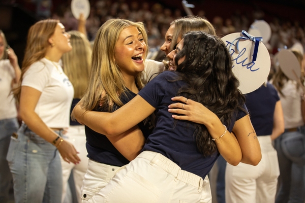 Three students hugging on bid day