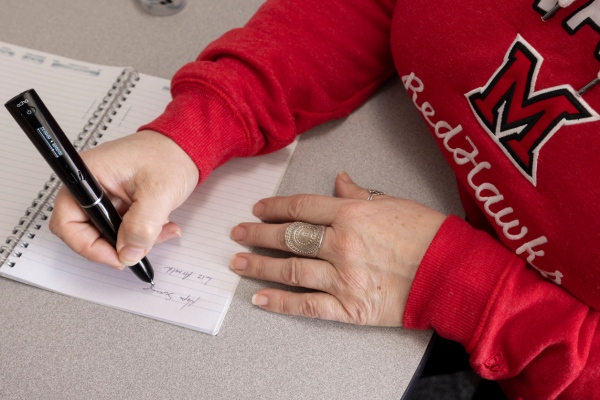 Close up of someone in a red Miami sweatshirt using a read-write pen.